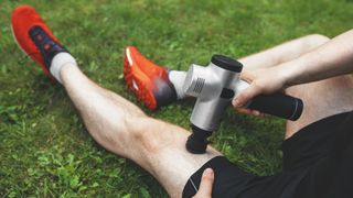 Man using massage gun on leg