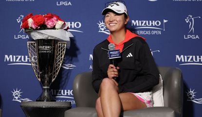 Zhang sits down on a chair next to the trophy