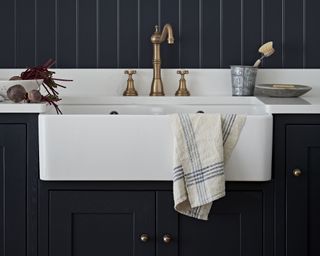 A large butlers sink with navy decorative wood paneling