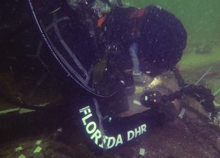 A photo shows one of Florida's "underwater archaeologists" examining wooden stakes found alongside the buried bodies.