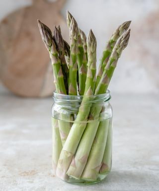 A bunch of asparagus stems in a jar of water