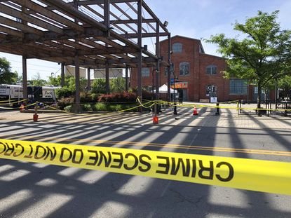 Police crime-scene tape keeps people away from the brick Roebling Wire Works building, background, in Trenton, N.J., hours after a shooting broke out there at an all-night art festival early 