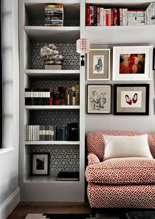 Built-in pale gray shelving around a red and white patterned couch in small apartment living room ideas.