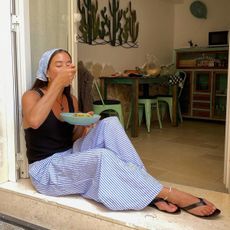 woman eating pasta in striped pants and a tank top