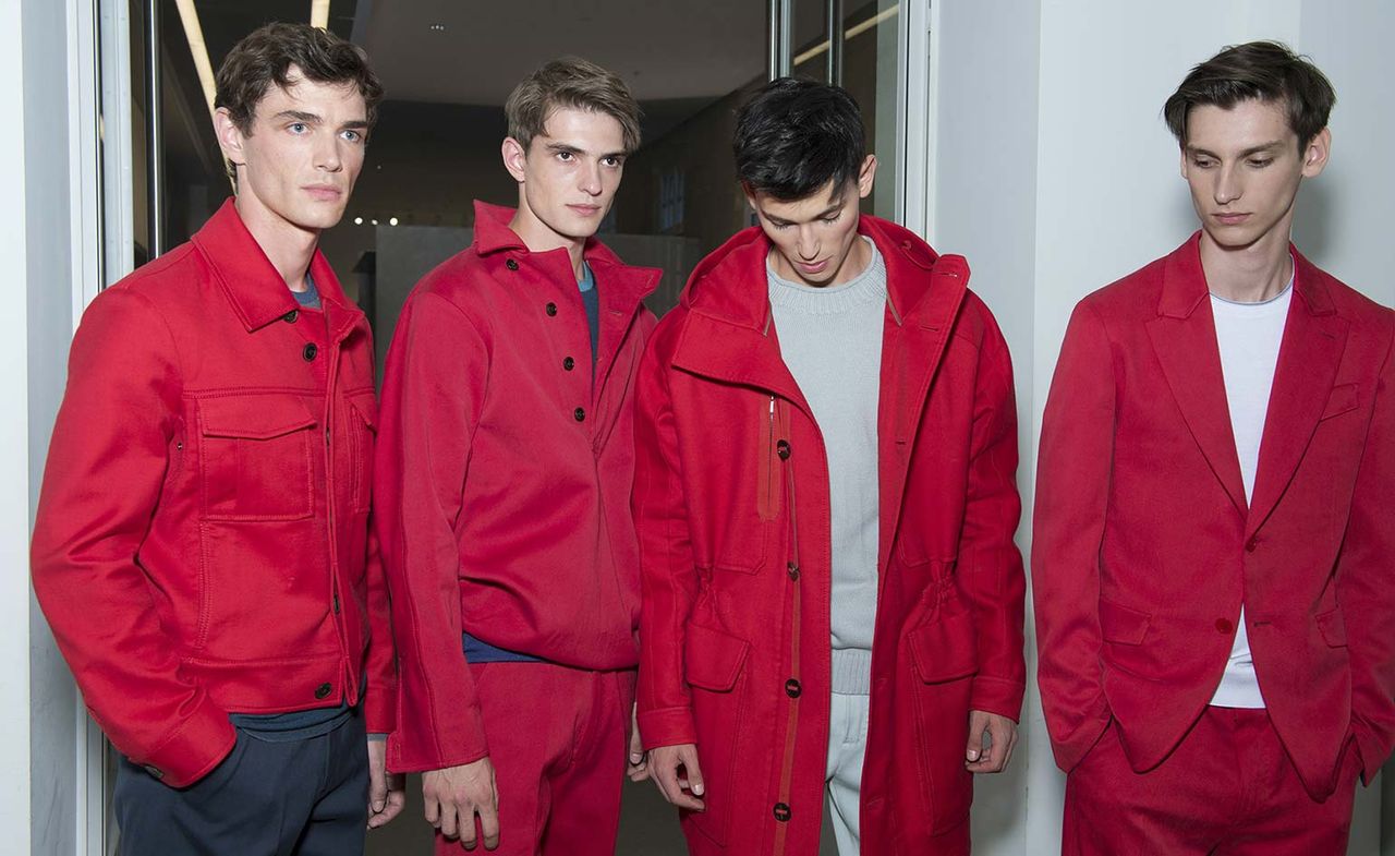 Four male models wearing clothing by Berluti in burgundy shades.