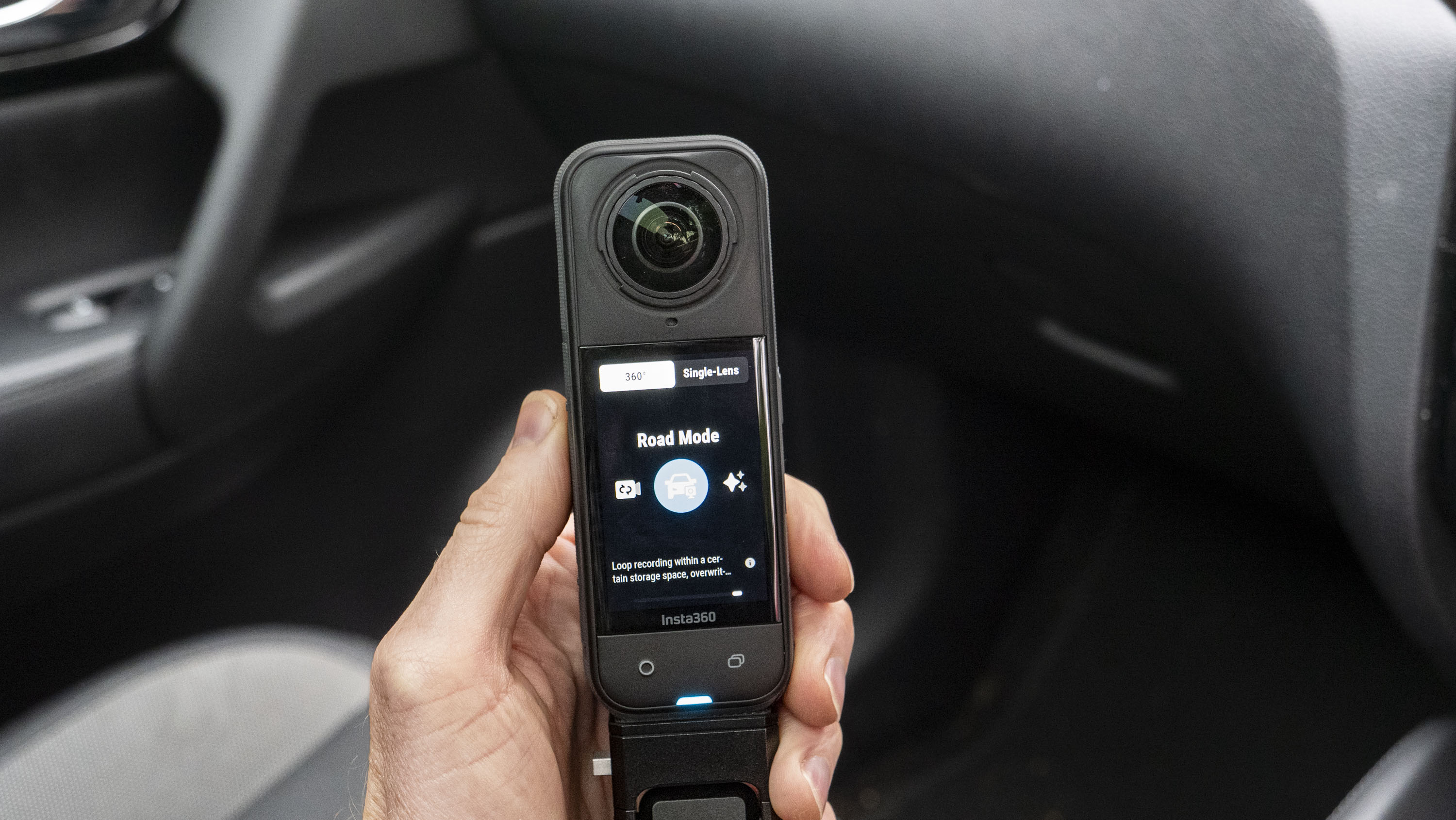 Insta360 X5 inside a car in user's hand, with road mode on the display