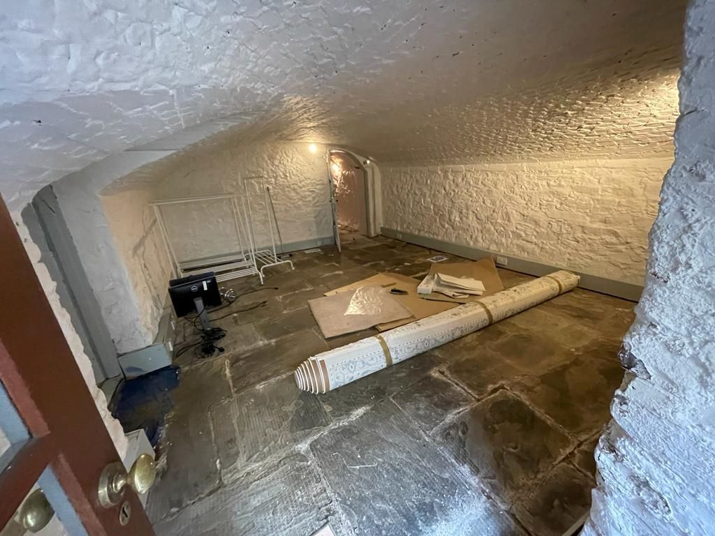 An underground room with painted brick walls and flagstone floor tiles