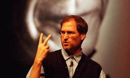Steve Jobs, speaking at a publishing conference in 1997, stands in front of a giant poster of Pablo Picasso, featured in Apple's landmark "Think Different" campaign.