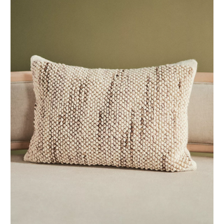 thick, tufted beige pillow with darker toned marl running through