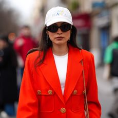 best sof moisturisers - Fer Millan wears a white cap, sunglasses , a white top, a bold red oversized blazer jacket 