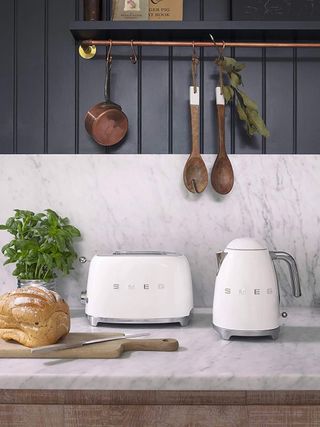 white smeg kettle and toaster in kitchen with marble worktop and backspalsh and blue paneled walls