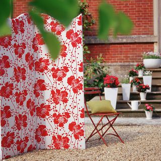red floral screen on gravel patio with red metal chair