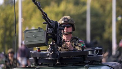 Polish soldier in tank holding gun during military parade