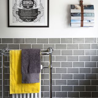 bathroom with grey brick wall towel rail and magazines hanged on wall
