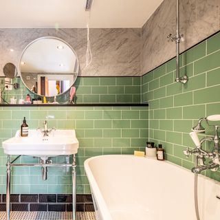 bathroom with green tiles on wall and rounded mirror