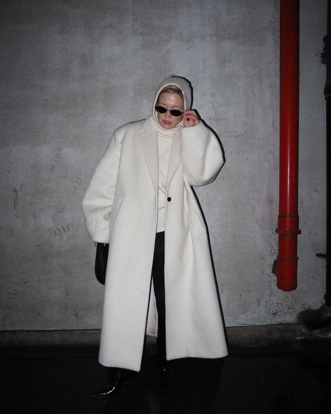 Alexis in an all white coat and jumper combo and black trousers