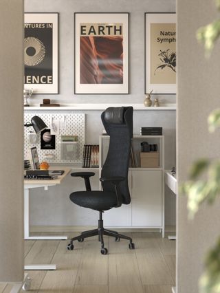 An office space with an office chair at a desk, with framed art and posters on the walls