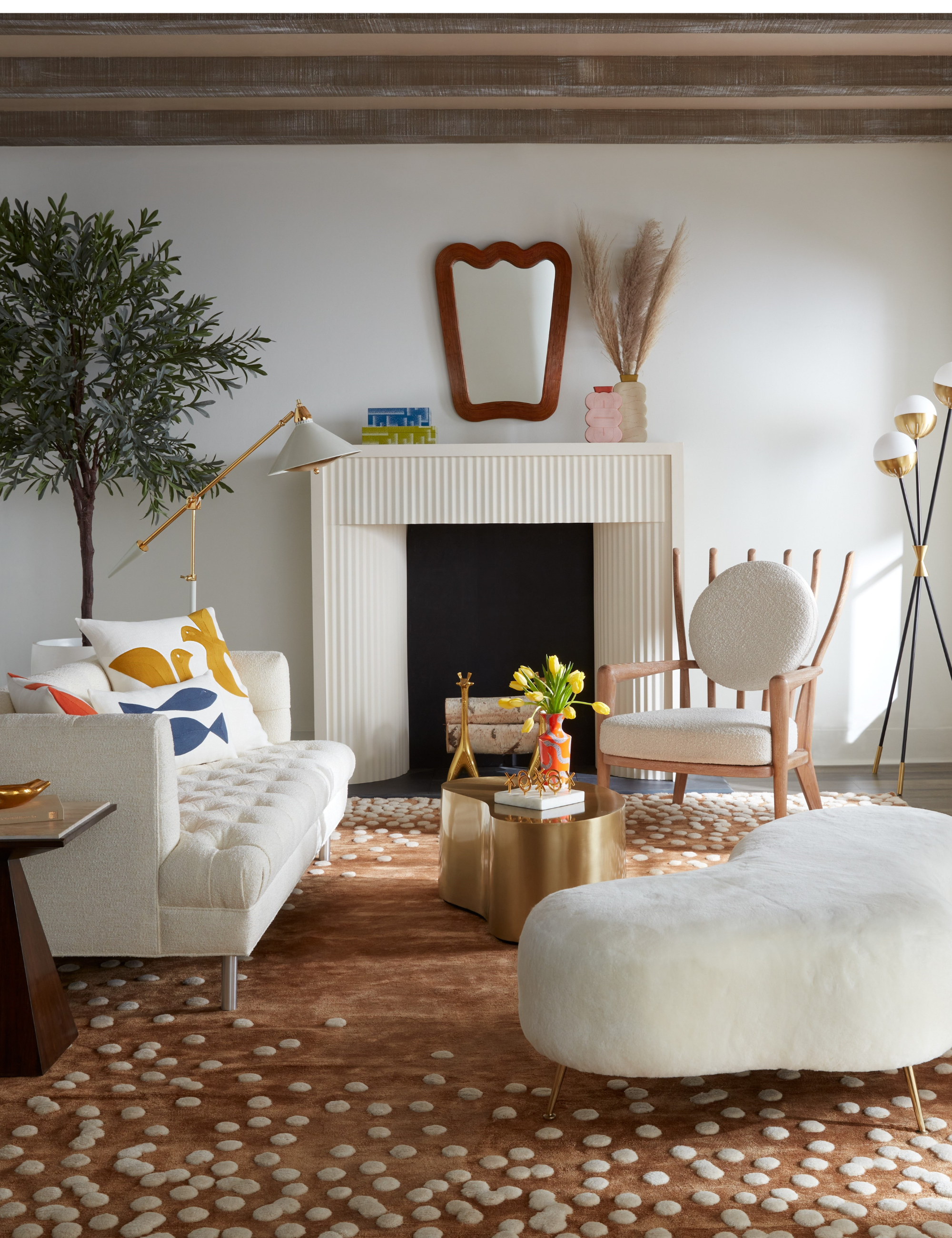 Bright living room featuring a brown fawn patterned rug, white furniture, and a sculptural wooden mirror above the fluted fireplace