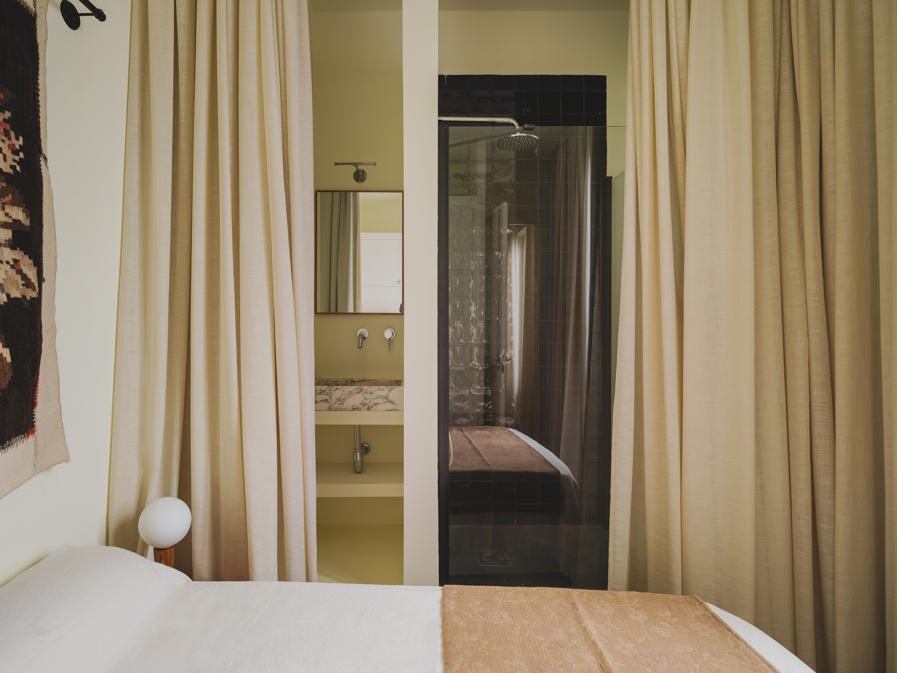 Curtains divide the bedroom from the bathroom.