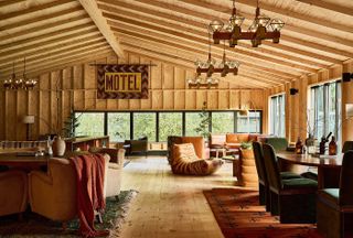 A wood and leather-drenched former motel features sculptural mid-century modern furniture, terracotta-hued rugs, and wide windows.