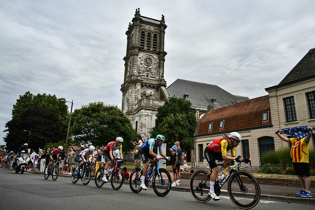 Cofidis team's French rider Benjamin Thomas (R) leads a breakaway past the Eglise catholique Saint-Martin church in Carvin, during the 1st stage of the 112th edition of the Tour de France cycling race, 184.9 km starting and finishing in Lille Metropole, northern France, on July 5, 2025. (Photo by Marco BERTORELLO / AFP)