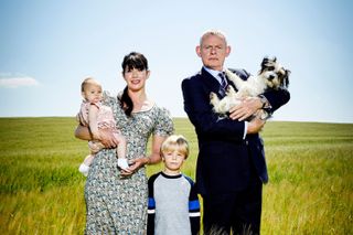 Doc Martin and his wife Louisa carrying their two children in a field