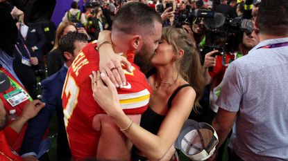 Taylor Swift wearing red lipstick while kissing Travis Kelce at the 2024 Super Bowl.