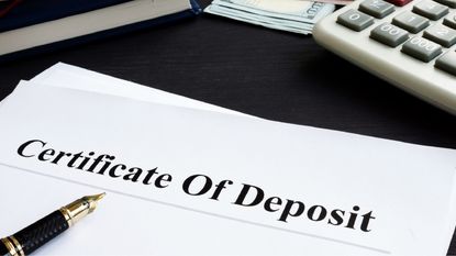 The words certificate of deposit written across a sheet of paper alongside a calculator.
