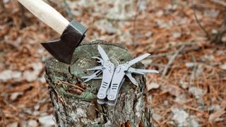 Camping axe and multitool on a tree stump