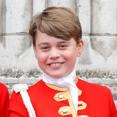 Prince George wears red uniform with gold adornments