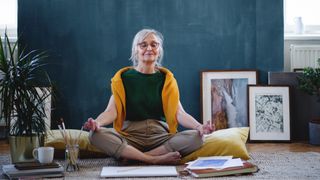 Woman meditating, sitting on floor in front of paintings