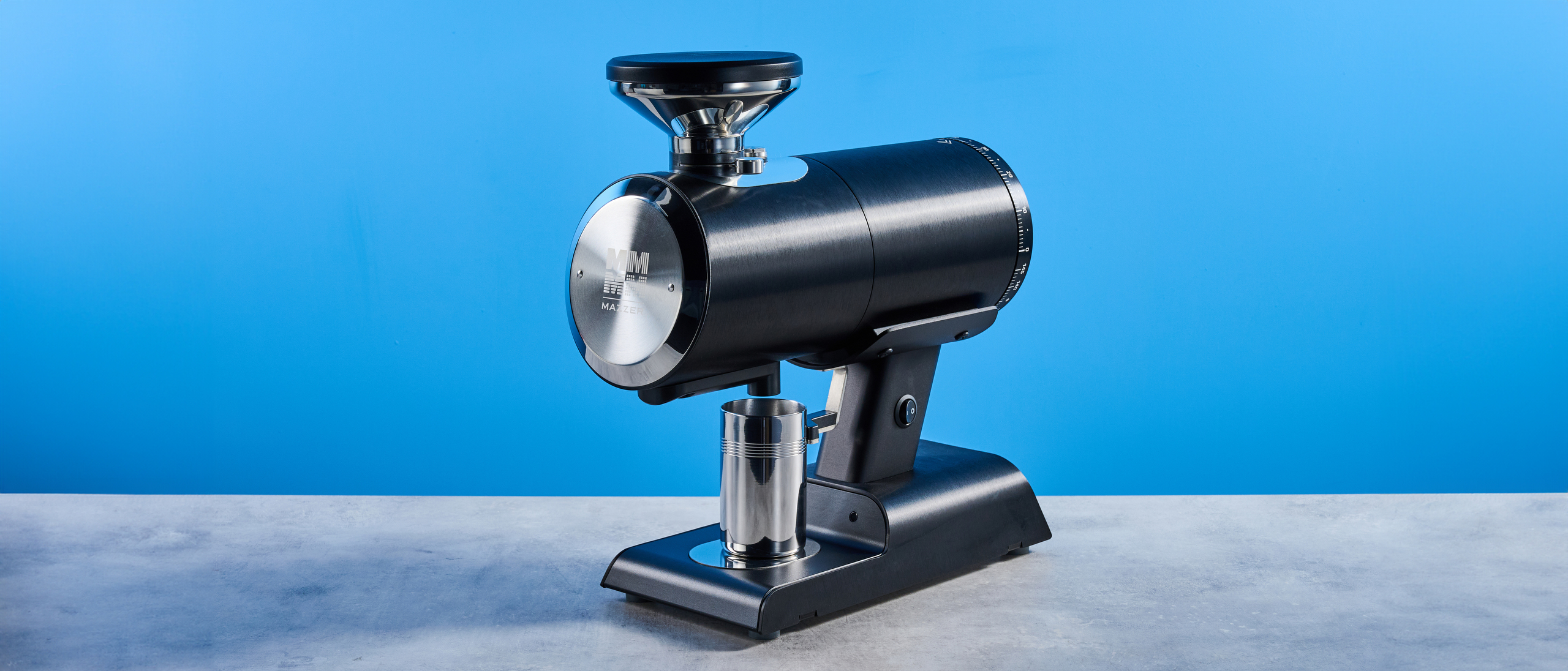 the mazzer philos coffee grinder in black and stainless steel photographed against a tom's guide blue background
