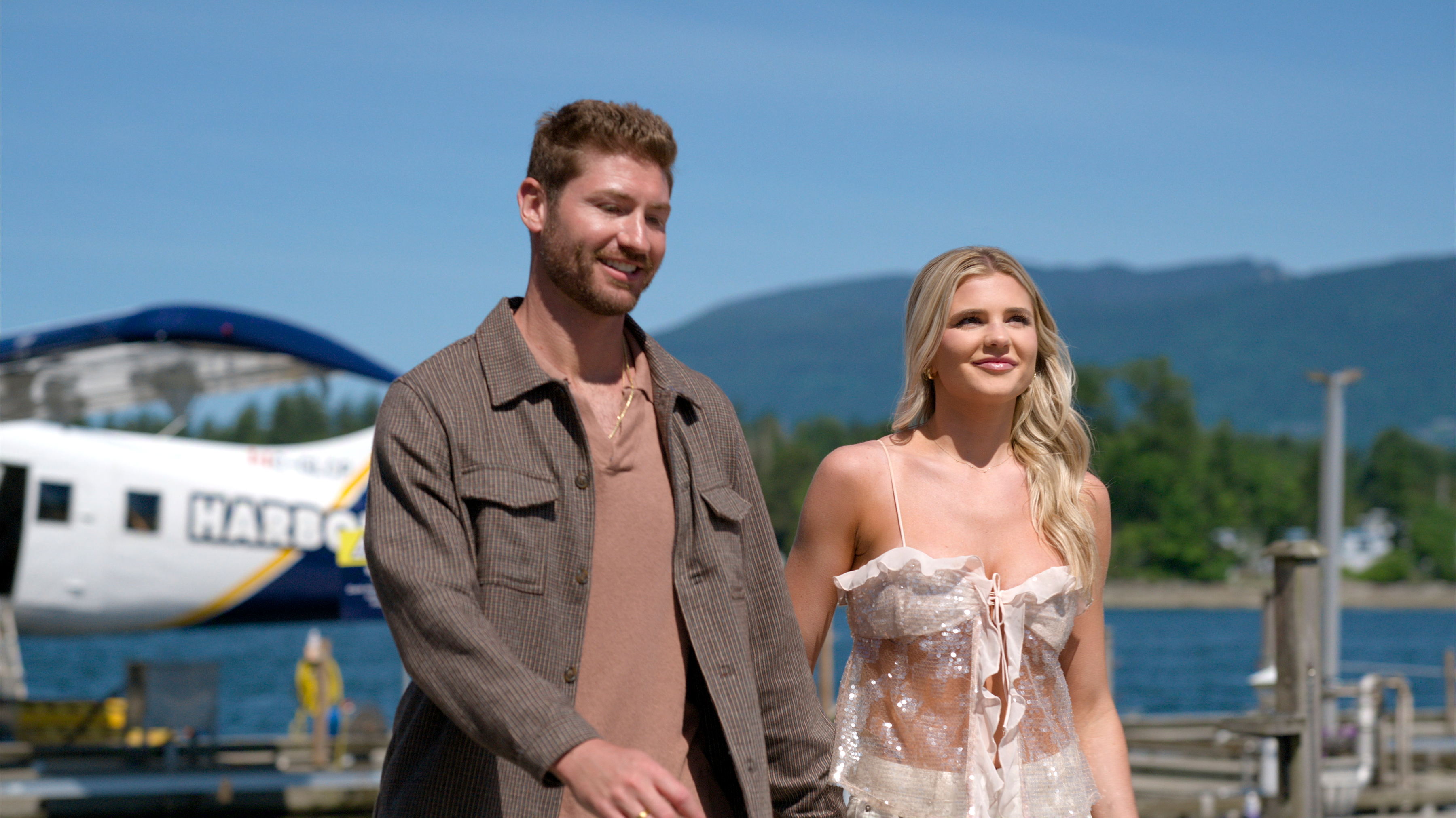 age of attraction couple libby and andrew on a date at a dock with a helicopter in the background in the netflix dating show