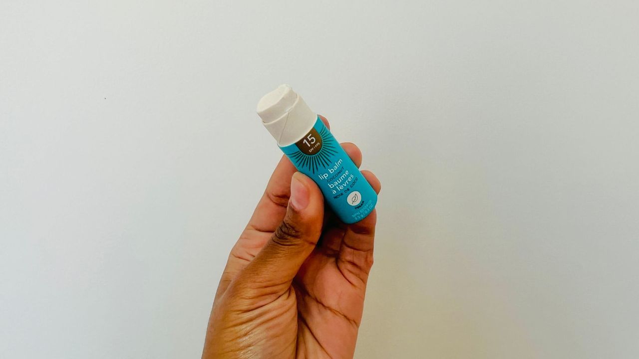 A person holding an opened Attitude SPF Lip balm.