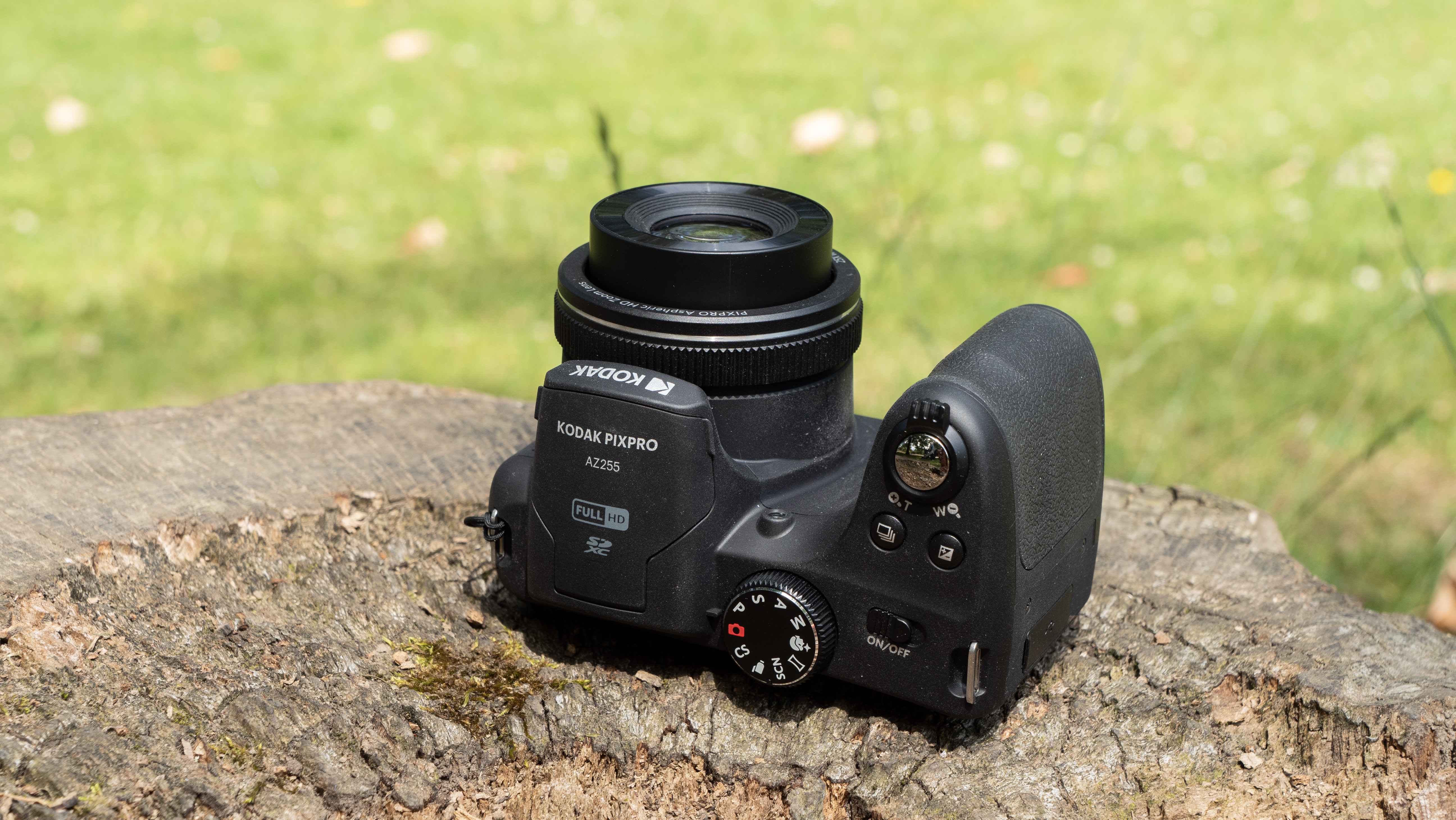 Kodak PixPro AZ255 digital camera in black on a stone surface in front of a green background outside