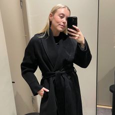 Woman wears black wool coat from COS