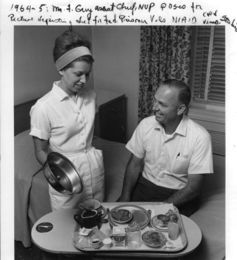 Caption reads: ‘1964-5: Mr. Grey, Assistant Chief, NVP (Normal Volunteer Program) poses for picture depicting diet for Fed Prisoners Vols, NIAID cold virus studies’.