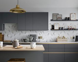 g shaped kitchen with grey cabinets, black and white backsplash tiling and wood countertops