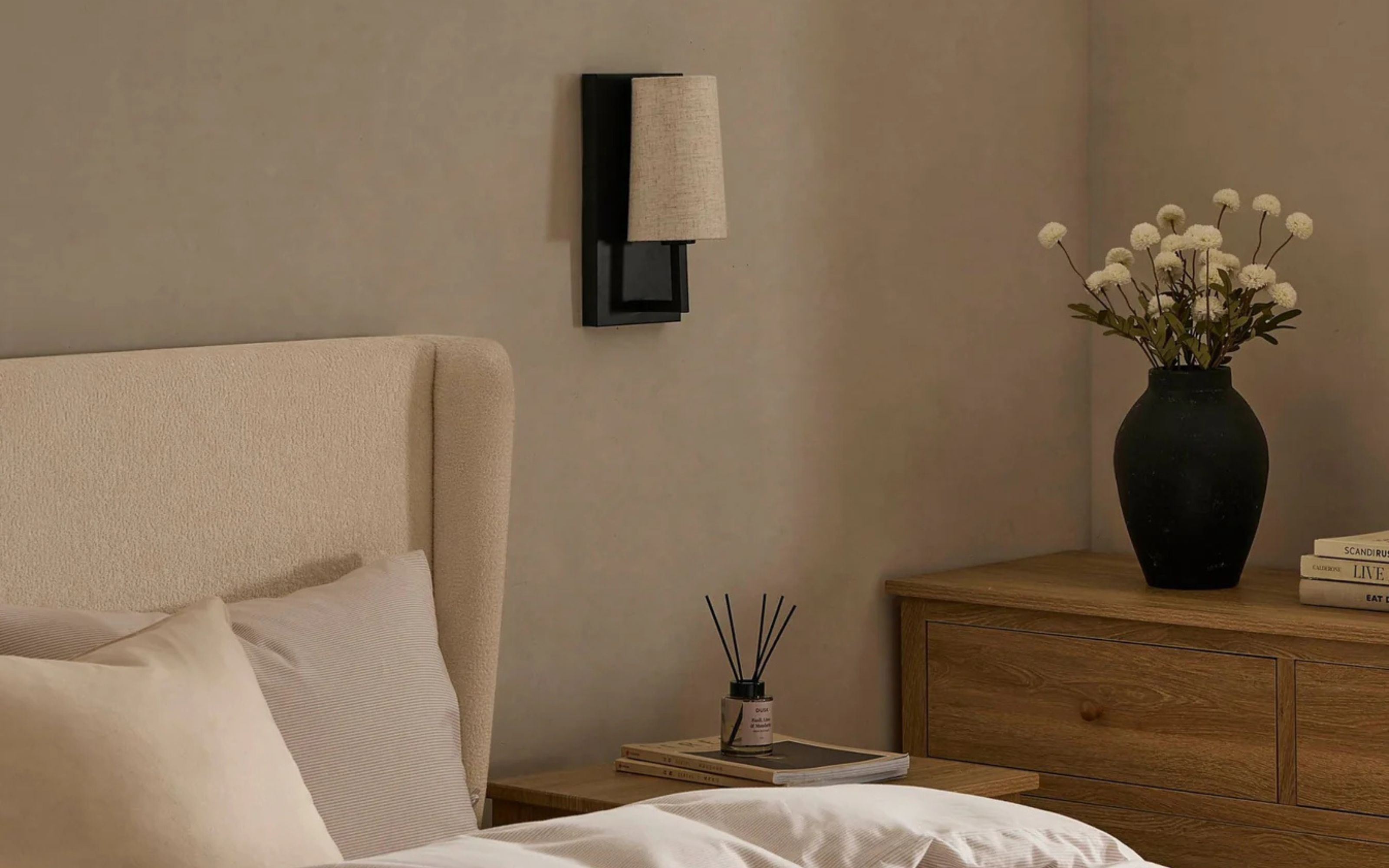 Alban LED Rechargeable Wall Light - Black - on bedroom wall with neutral decor and bed frame, wooden chest of drawers and black vase