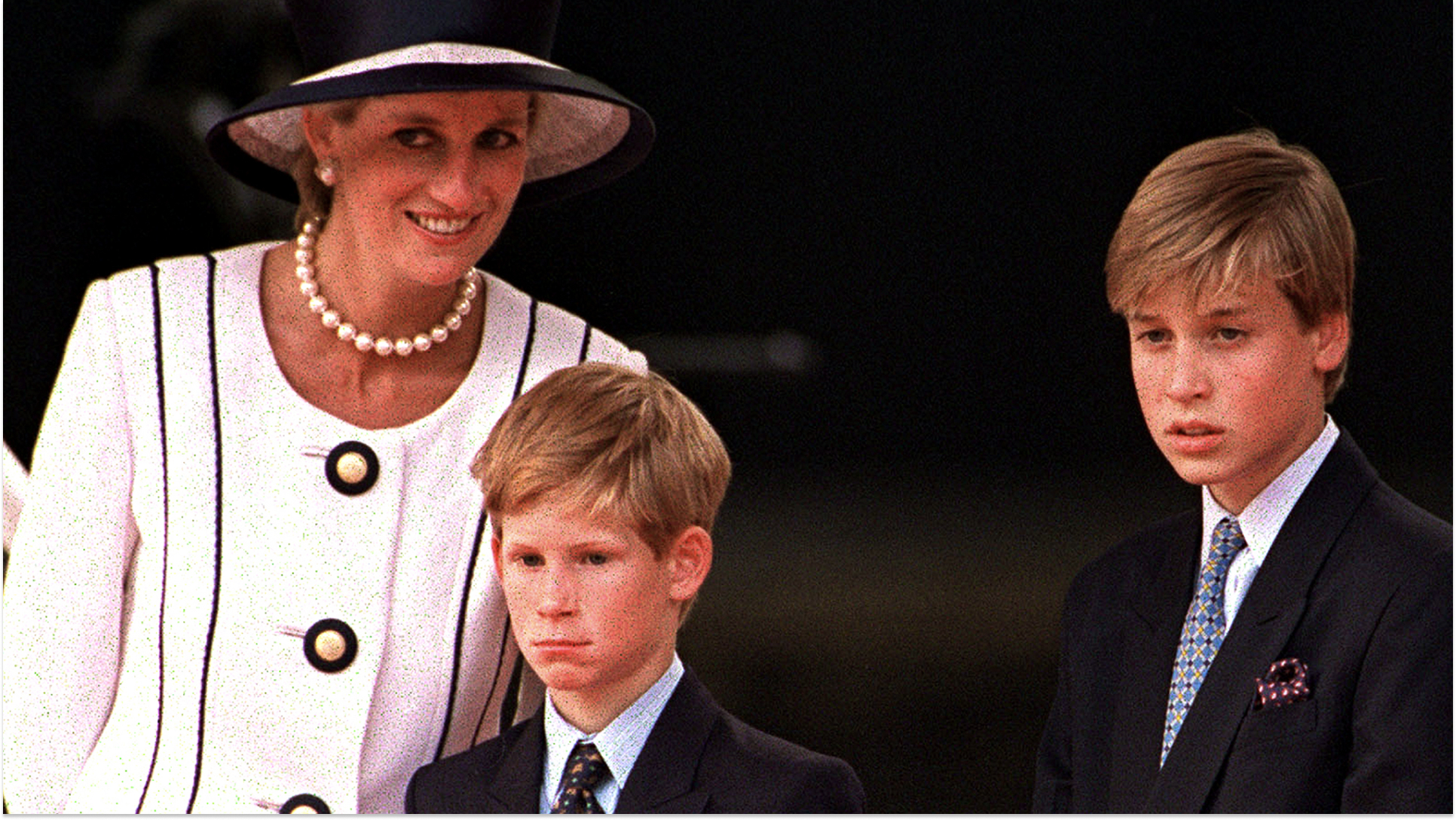 Princess Diana wears a white suit and matching hat with black piping, and poses with her sons Prince Harry and Prince William