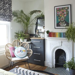 Fireplace with white mantelpiece surrounded by a few pot plants and books on top of mantelpiece