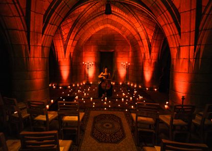 A woman plays the violin in a crypt