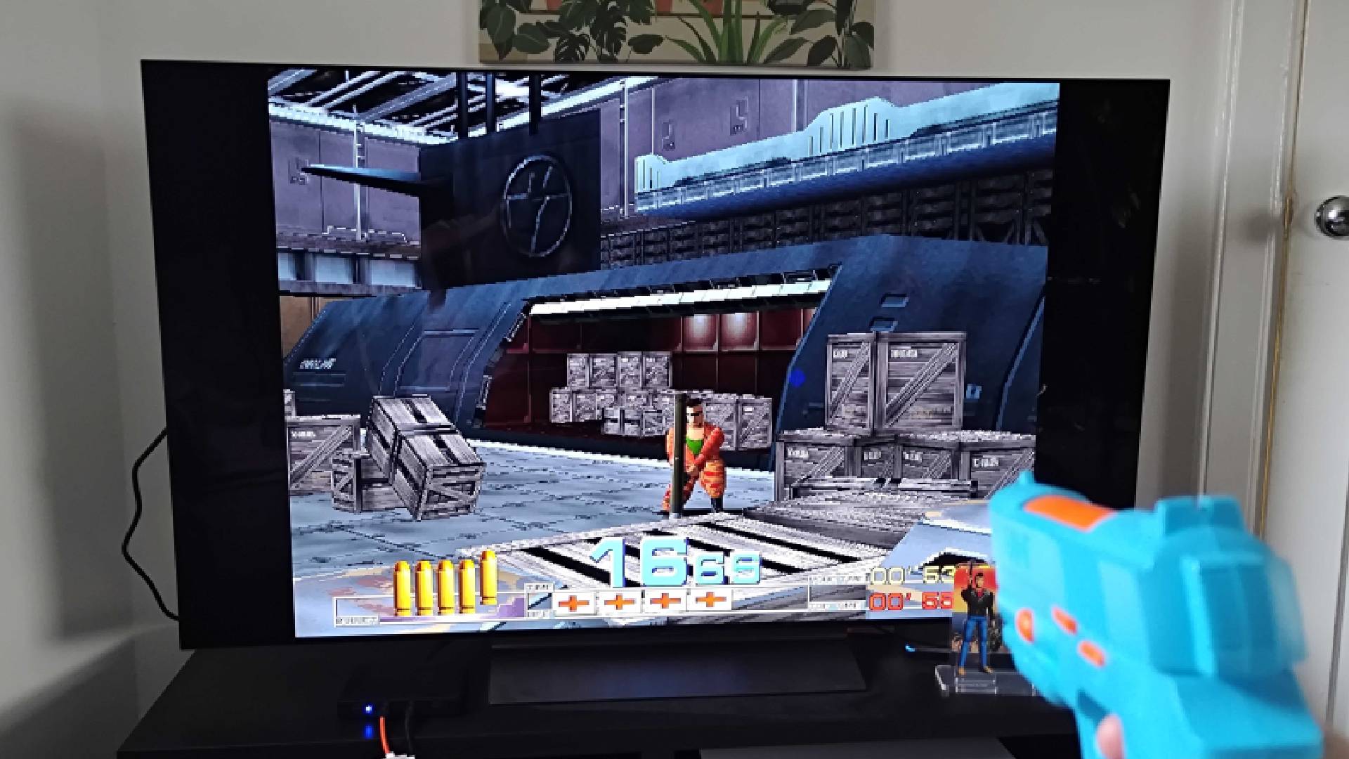 G&#039;AIM&#039;E Time Crisis console connected to TV with gameplay on screen.