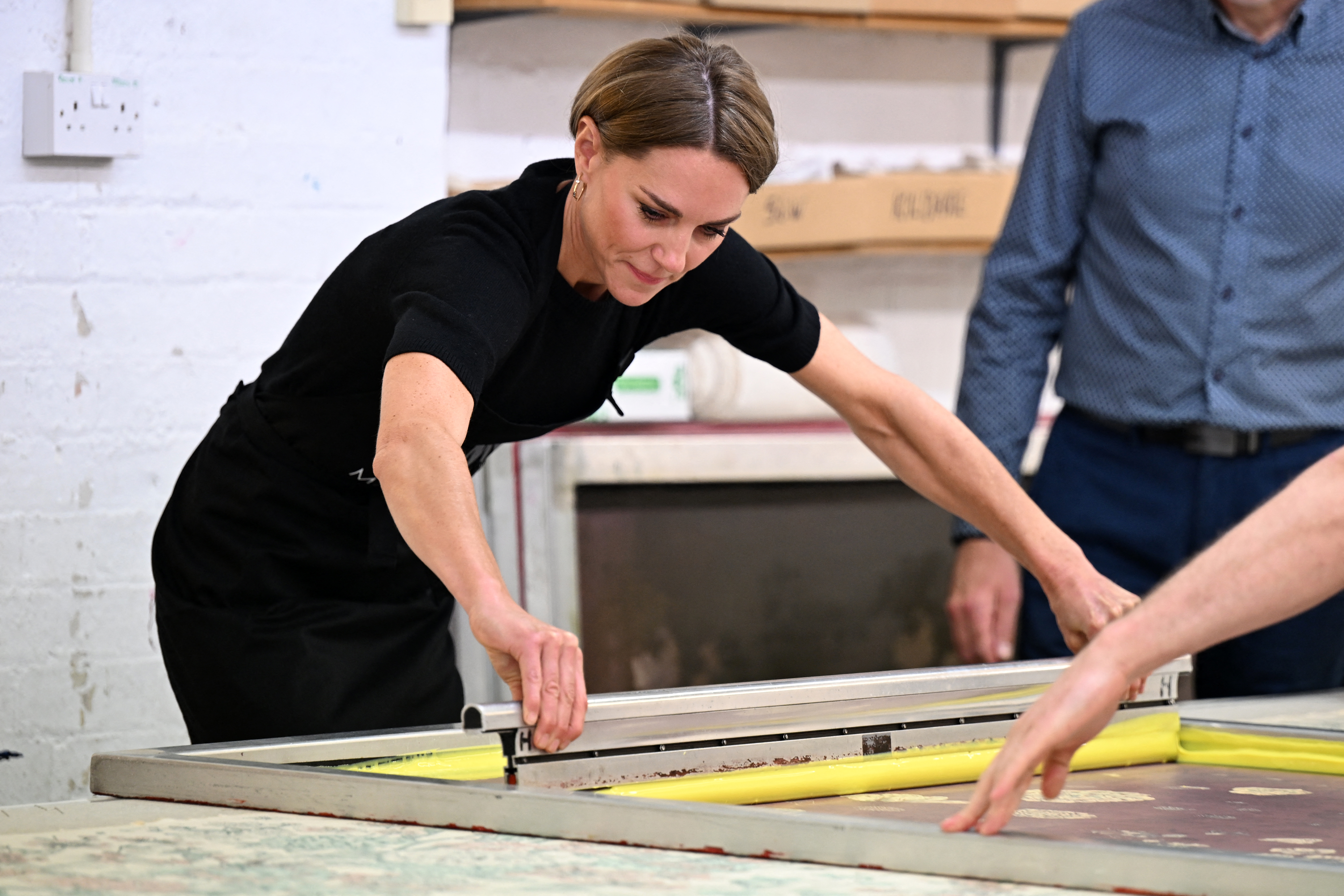 Princess Kate wearing a black top using a squeegee on fabric