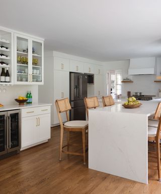 A white kitchen warmed up with wood flooring, wooden shelves, and wood decor