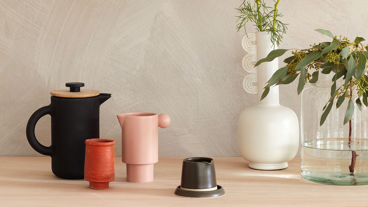 Mugs and teapot and decorative vase displayed on wooden surface