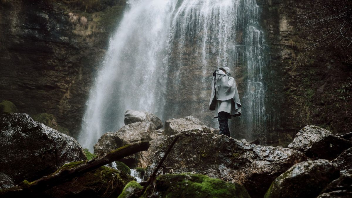 Photographer wearing DxO Photo Storm Cape beneath waterfall 