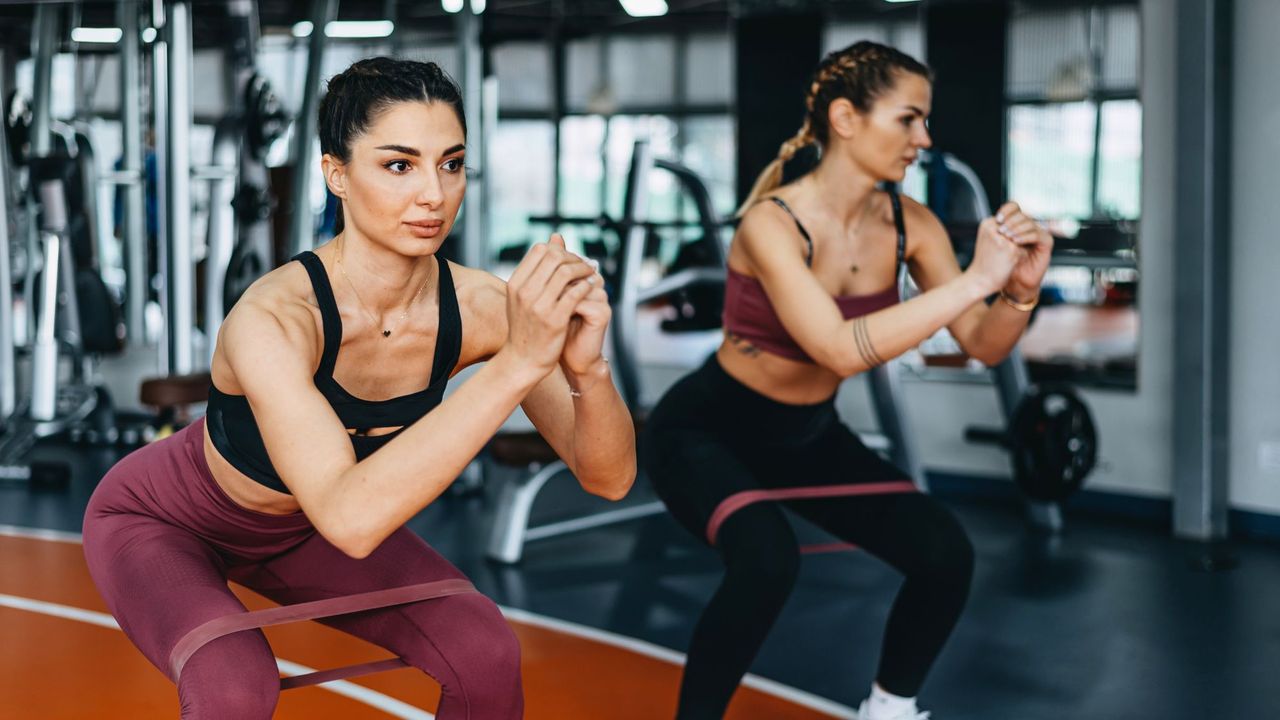 Two women working out with resistance bands in the gym