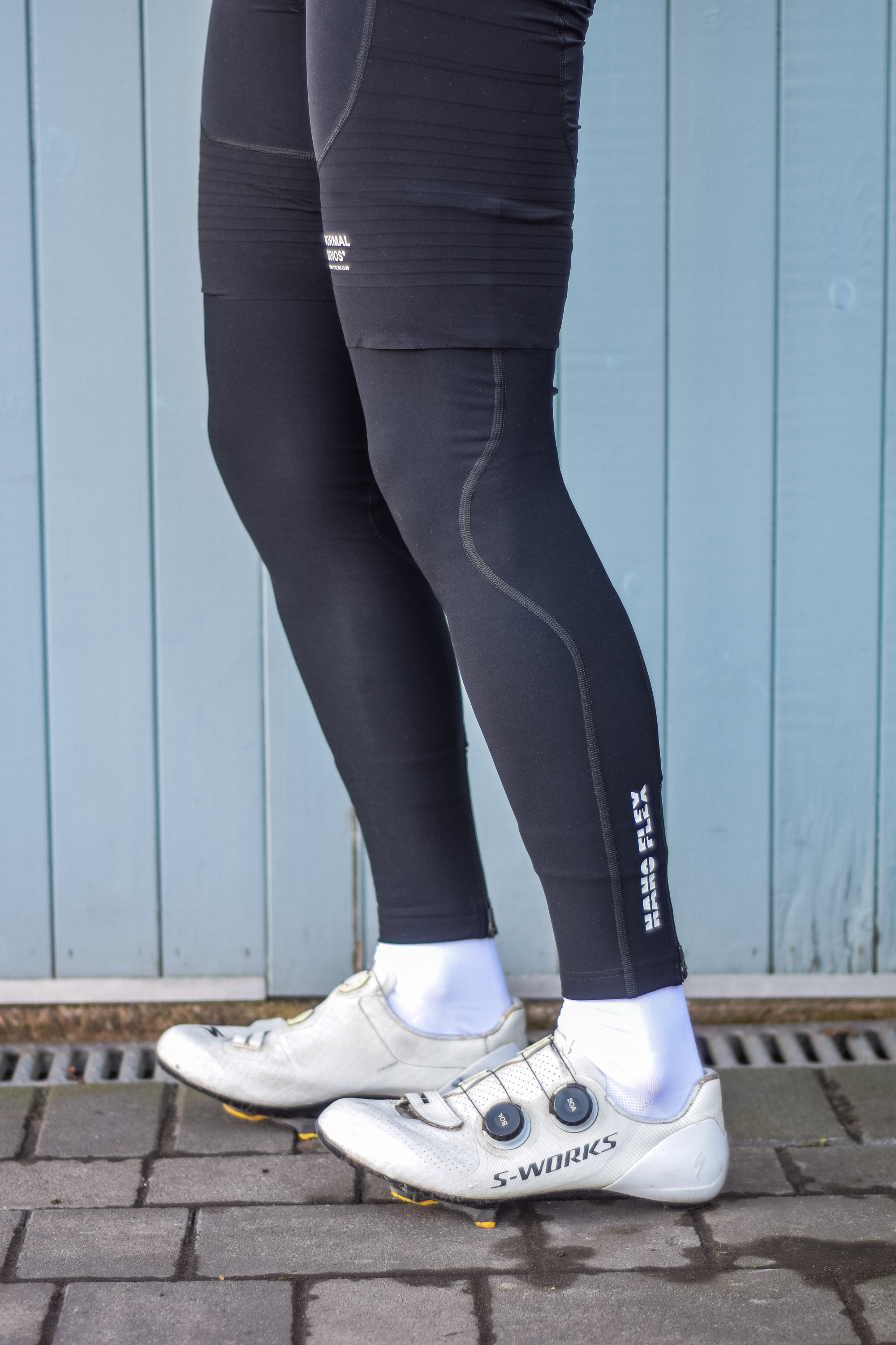 A man wearing cycling shorts and leg warmers in front of a blue door 