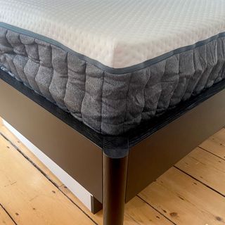 The Emma Hybrid Original mattress being tested in a bedroom with a wooden floor